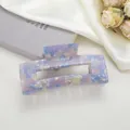 Detail of a rectangular marble acetate hair claw clip on soft silk fabric background - Sky Blue