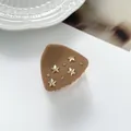 Detail view of caramel brown shark hair claw with gold stars and sparkling rhinestones - Brown