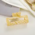Close-up of a square marbled yellow acetate hair claw clip on silk fabric background - Yellow