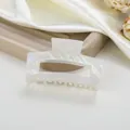 Detalle de la pinza de pelo de acetato marmoleado blanco con diseño hueco y brillo irisado - Blanco lechoso
