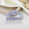 Detalle macro de pinza de pelo de acetato con patrón de mármol azul en fondo blanco - Azul Metálico