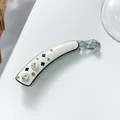Detailaufnahme der Bananen-Haarklammer aus Acetat mit Kristallen und Kleemotiven - Weiß