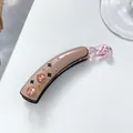 Detail of banana clip with pink rhinestones and black clover on beige acetate - Pink