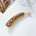 Close-up of brown acetate banana clip with orange rhinestones and clover pattern - Coffee