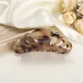 Detailed close-up of a hollow tortoise shell pattern hair claw clip on silk fabric - 10.5cm / Ink Brown