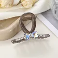 Detail of dark brown jelly shark clip featuring iridescent heart bow and rhinestones - 7cm / Dark Gray