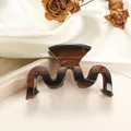 Primer plano de pinza de pelo ondulada con efecto carey y degradado ámbar suave - Ámbar