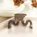 Detalle de pinza para el pelo ondulada marrón traslúcido en elegante fondo de satén blanco - Tostado