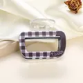 Detail of purple checkered acrylic hair claw clip with Duckling Teenagers logo on silk - 6.5cm / Purple