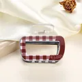 Close-up of red plaid acrylic claw clip with Dueling Teenagers logo and duck pattern - 6.5cm / Dark Red