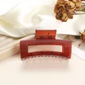 Close-up of a large amber hair claw clip on silk fabric with floral decor accents - 8cm / Brick Red