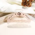 Detalle de pinza de resina rosa con diamante central grande y patrones florales de pedrería - Mediano / Naranja