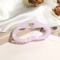 Makro-Detail einer lavendelfarbenen Haarklammer mit goldener Feder auf Seide - Rosa-Lila