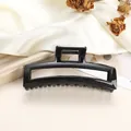 Close-up of a glossy black hollow rectangular hair claw clip on elegant silk fabric - Solid Black