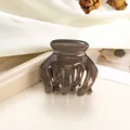 Close-up of translucent amber small hair claw clip on a white satin and prop display - Small / Dark Brown