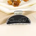 Detailed macro view of black medium shark hair claw clip with Goodluck engraving - 9cm / Black