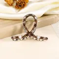 Detailopname van een retro haarclip met ruitjespatroon en goudkleurige metalen veer - Bruin