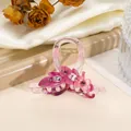Detail van een acryl haarklem met paarse bloemen en schitterende strass-steentjes - Felroze
