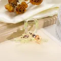 Nahaufnahme einer Blumen-Haarklammer aus Acryl mit bernsteinfarbenem Harz und Strass - Hellgrün