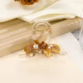 Dettaglio molletta ambra per capelli con fiori marroni e cristalli su tessuto di seta - Oro