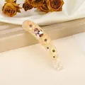 Detail of amber resin banana hair clip with floral relief and large oval gemstone inlay - Orange