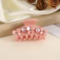 Detailed view of pink bow hair claw clip with heart rhinestones and flower accents - Pink