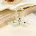 Macro detail of mint green bow claw clip with pink rhinestones and gold spring - Green