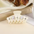 Detail of cream bow hair claw clip with crystal rhinestones on elegant silk background - White