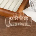 Close-up of clear amber flower hair claw clip with brown rhinestones and gold spring - Orange