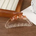 Detail of semi-circular amber flower hair claw clip with rhinestones on wood background - Orange