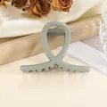 Detailansicht einer matten salbeigrünen Haarklammer mit Kreuzdesign und Metallfeder - Grau