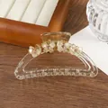 Detailopname van amberkleurige vlinderhaarklem met strassteentjes op houten dienblad - Champagnegoud