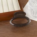 Detail view of a translucent charcoal grey jelly hair claw clip with a glossy resin finish - Brown