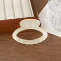 Detail of a creamy beige translucent resin hair claw clip with oval hollow design - Off White