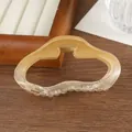 Detail of a wavy amber translucent hair claw clip with a strong gold metal spring - Gradient Yellow