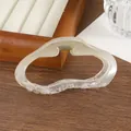 Vue détaillée d'une pince à cheveux mate crème translucide sur une table en bois - Vert clair