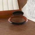 Close-up of a brown gradient hair claw clip with oval cutout on a wooden jewelry tray - Coffee