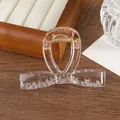 Detalle de pinza para el pelo rosa transparente con muelle dorado sobre madera - Champán dorado