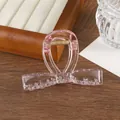 Detalle de pinza para el pelo con lazo rosa transparente y muelle dorado en bandeja - Rosa