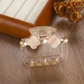 Detailed macro view of a rectangular transparent hair claw with amber crystals and floral petals - 6.5cm / Nude