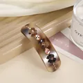 Detailed shot of amber hair clip with 3D floral accents and champagne rhinestones - Coffee