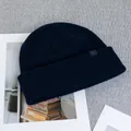 Detailed close-up of navy blue wool knit beanie with woven brand label and rib texture - One Size(Elastic) / Navy Blue
