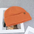 Close-up of orange wool beanie featuring a folded brim and brown square leather logo patch - One Size(Elastic) / Pumpkin Orange