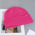 Detail of bright pink knitted wool beanie featuring a textured ribbed pattern and AIM logo - Rose Red