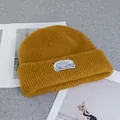 Close-up of ginger ribbed wool beanie with a mountain graphic brand label on the fold - Stretchy / Yellow