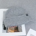 Detail of grey wool beanie with AIM leather brand tag on a textured magazine background - One Size(Elastic) / Light Gray