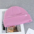 Detail of pink wool beanie showing fine knit texture and decorative brand logo tag - Pink