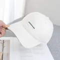Close-up of the KIVEFAH embroidered logo on a cream canvas baseball cap for women - Adjustable / Off White
