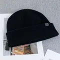 Detailed view of black wool knit beanie featuring a grey woven mountain logo tag - One Size(Elastic) / Black