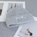 Detail of light grey knit beanie with a woven winter landscape patch and cozy wool texture - Stretchy / Light Gray